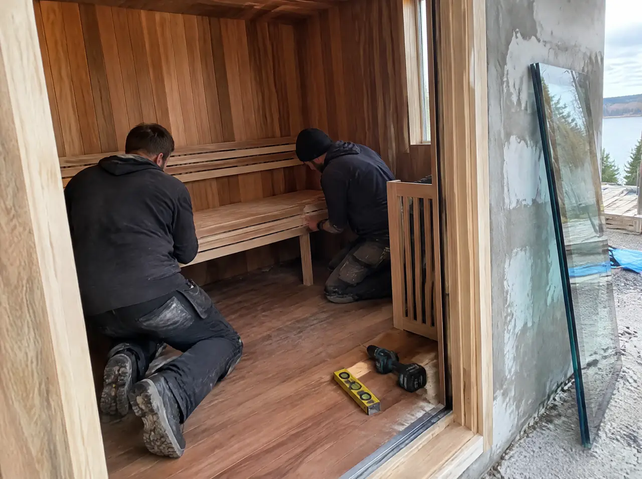Installers fitting a bench in a teak and cedar sauna cabin